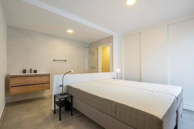 Un dormitorio realizado en colores blancos con toque de materiales naturales para crear un espacio limpio y acogedor
